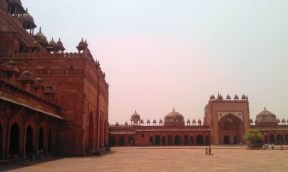 A plaza inside Agra Fort, with a large building on the left and a wall along the far side, with arched portico along it.