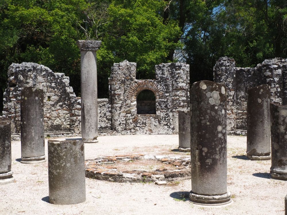 A circle of round stone pillars around a circle of stones on the ground.
