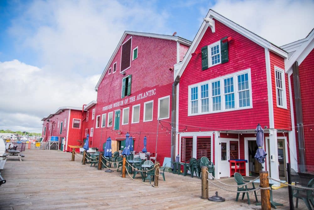 Several bright red wooden buildings in a row, one of which reads "Fisheries Museum of the Atlantic."
