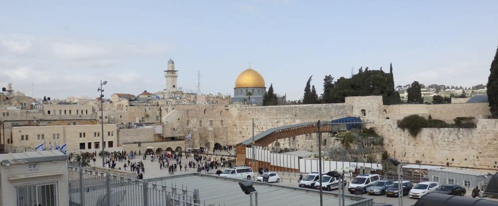 A view of the plaza with the Western Wall beyond it, the bridge leading to the top where the Dome of the Rock's golden dome is visible.