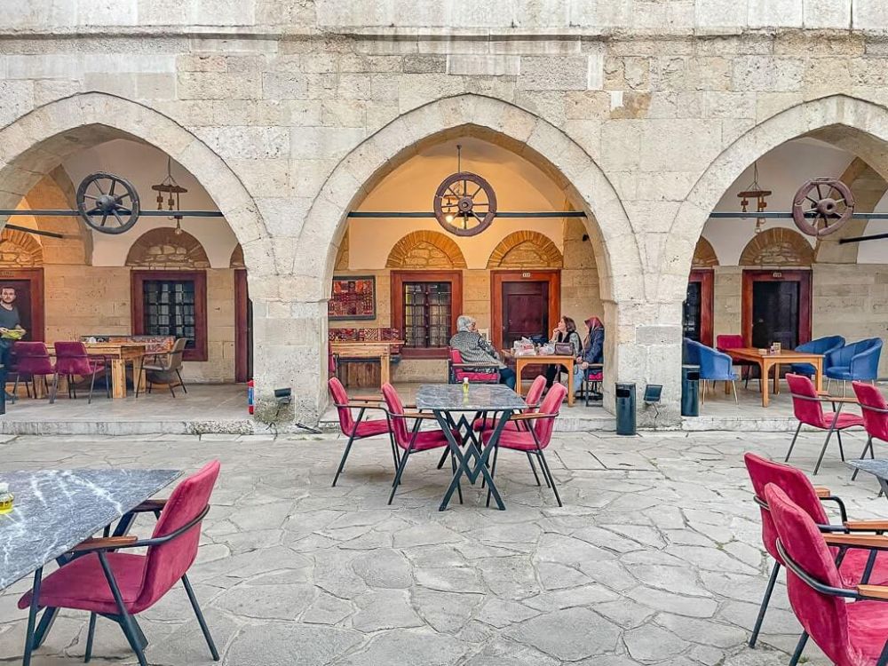 A courtyard set with tables, with a series of archways in the background.