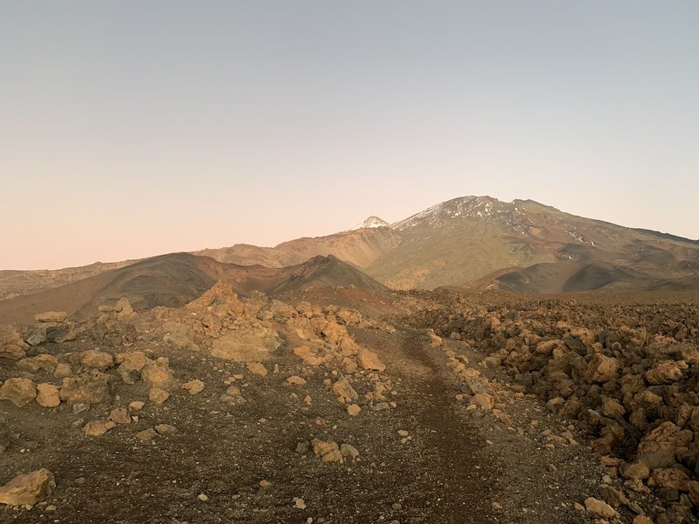 A view of the peak of Mount Teide: rocky ground and a snow-dusted peak.