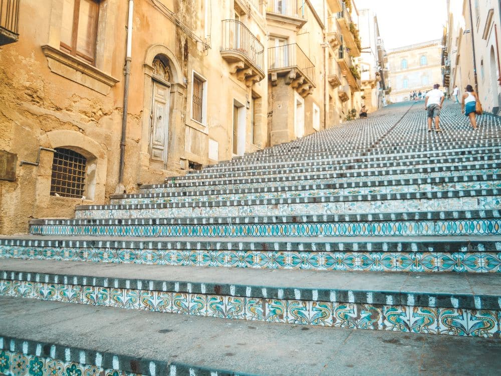 A wide street that is a staircase, with each stair tread lined with colorful tiles.