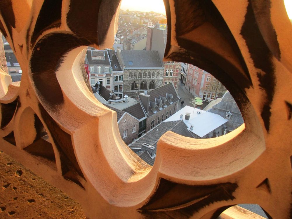 A view through a decorative fleur-de-lis of the town of Aachen from the tower.