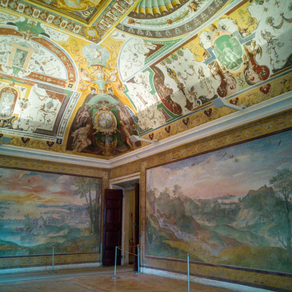 A room with ornate frescoes on the ceiling and both walls that are visible.