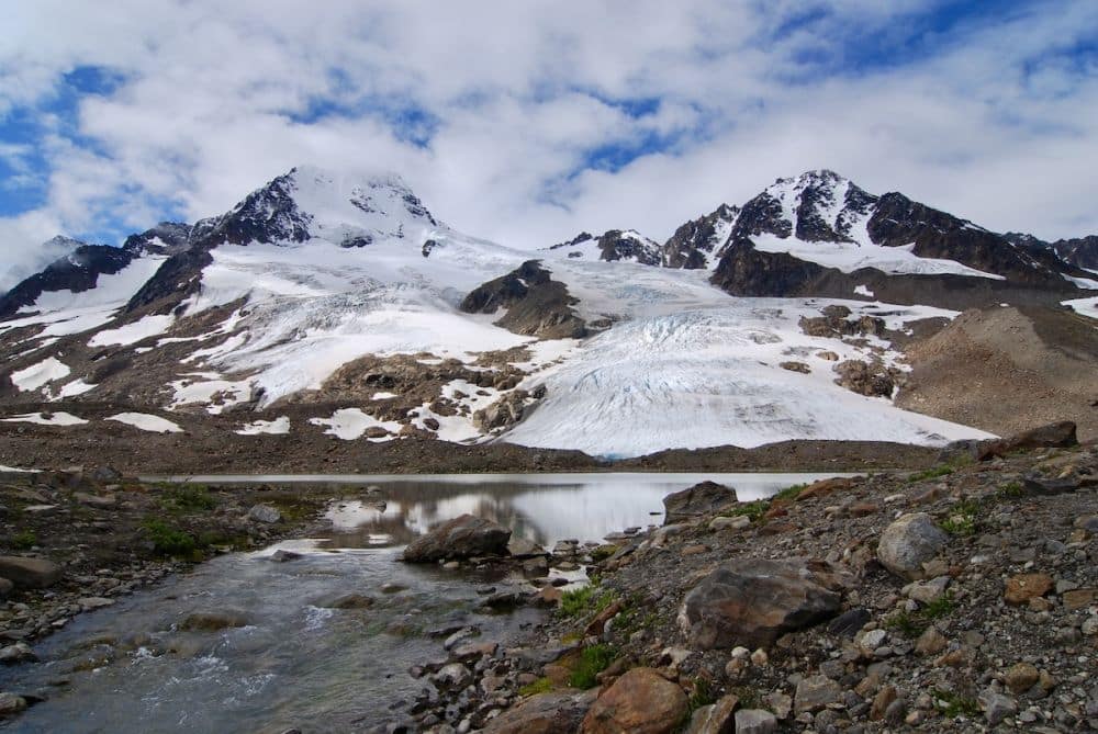 A view across a lake at a snow-capped mountain with a glacier down its side.