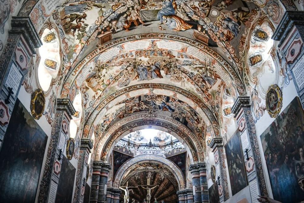 arched roof of a church covered in paintings.