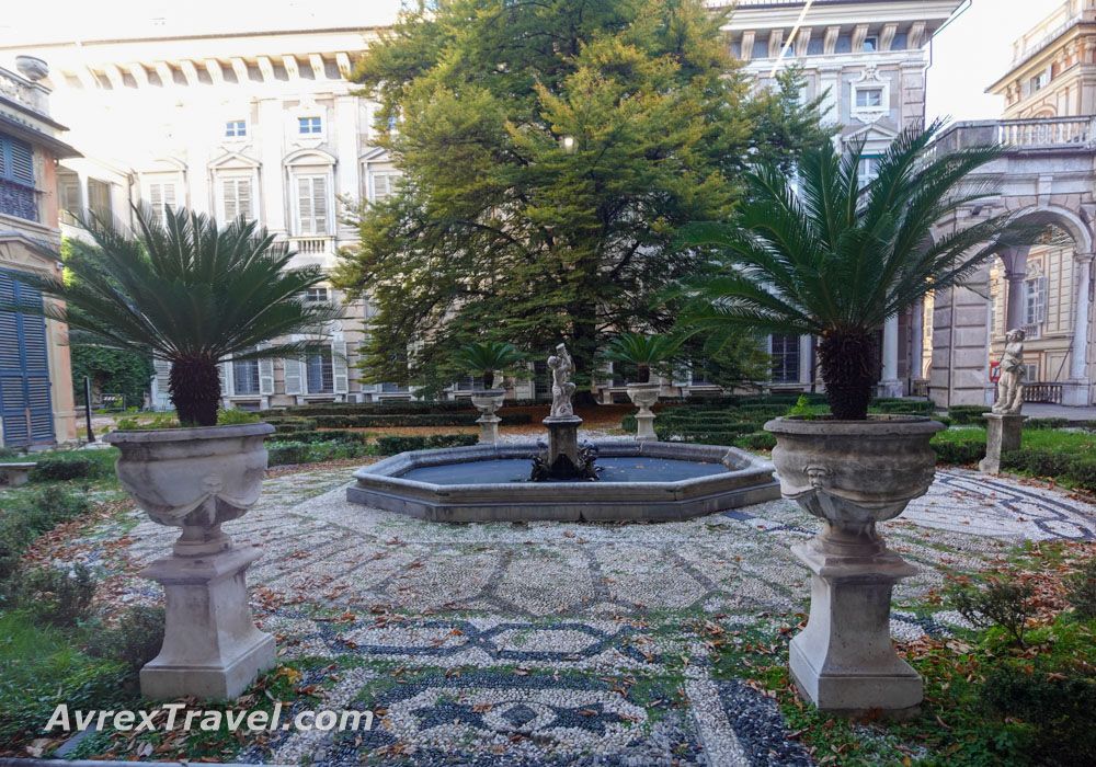 A fountain in a courtyard, paved with decorative stonework like a mosaic.