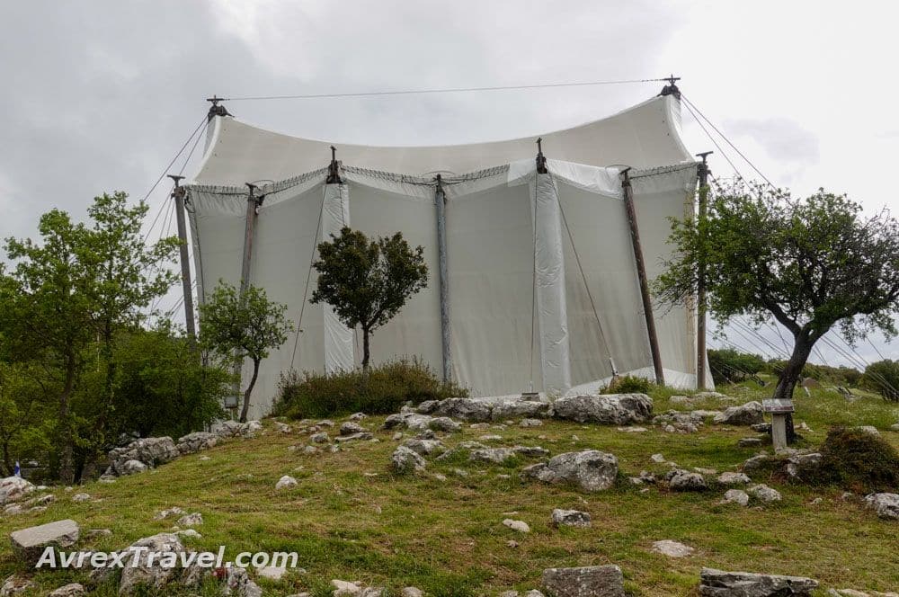 A large white tent, with a few small trees outside it.