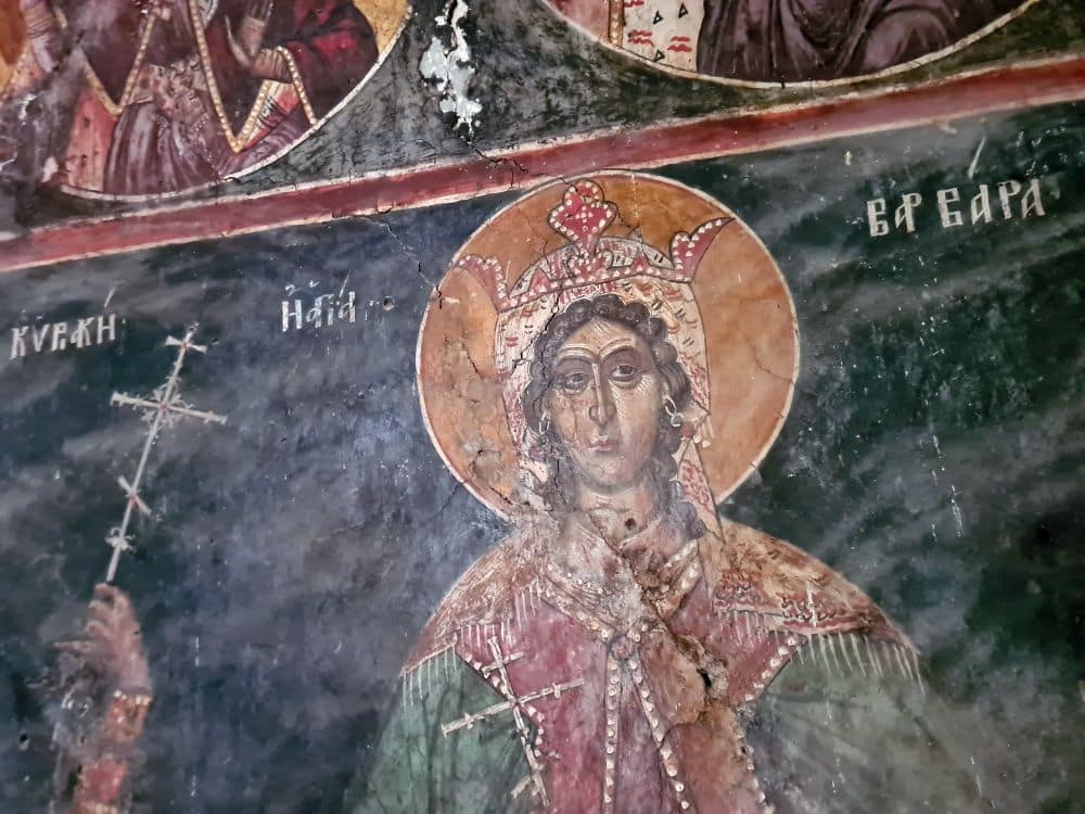 Fresco of a saint in robes with a big golden halo.