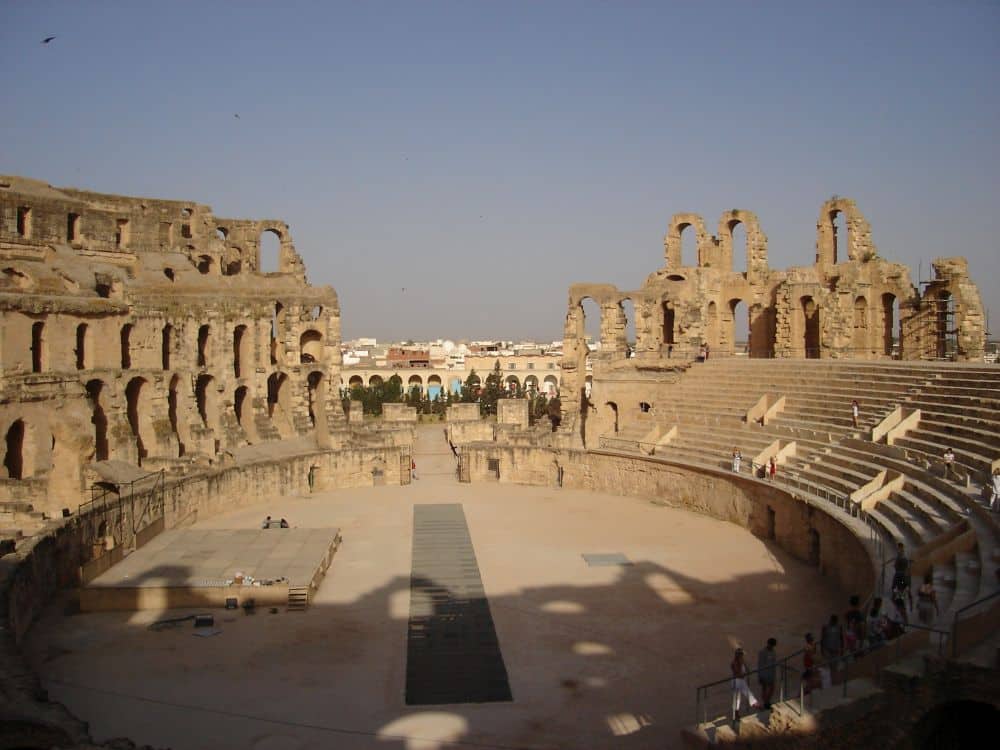 A view of the inside of the amphitheatre of El Jem - partial walls and some newer bleachers on the right.