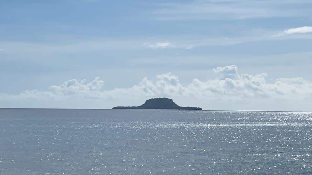 Far across the water, an island shaped like a hat, high in the middle.