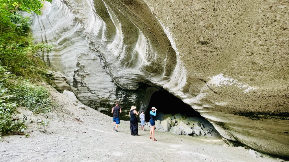 Tourists stand at the mouth of a cave.