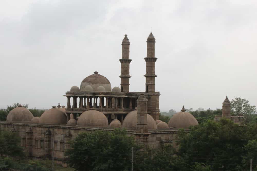 View of a mosque with 2 minarets, one large porticoed dome and many smaller domes.