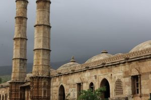 A mosque with arched entryways, domes on the roof and two very tall minarets.