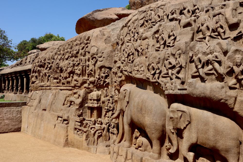 A wall with intricate sculptures of people and elephants.