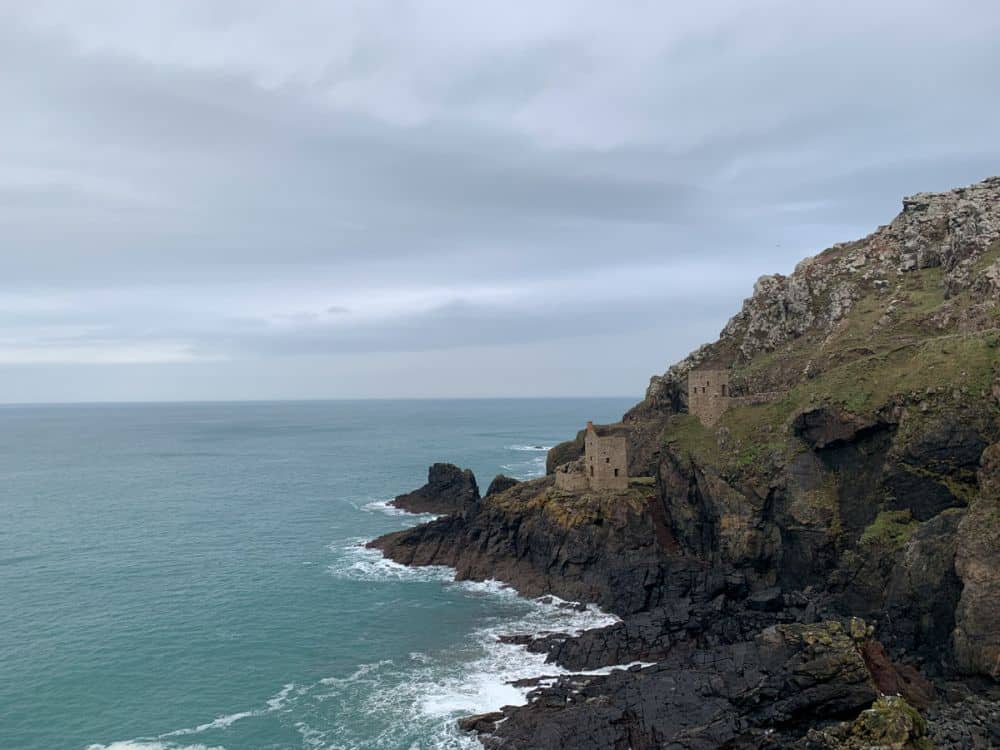 Craggy cliff with steep drops to the sea. A ruined mine perched halfway up the cliff.