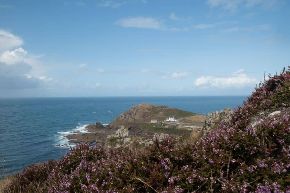 A rocky peninsula extends into the sea, with a scattering of old mine buildings on it.