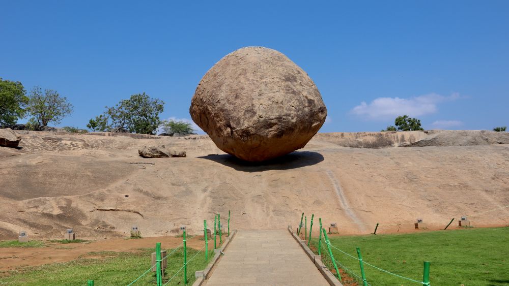 A very large round boulder poised on a slope.