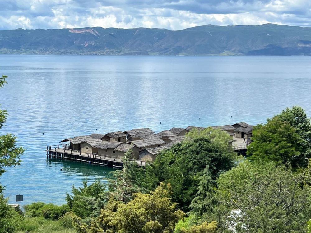 Looking down at Lake Ohrid, a cluster of small houses juts out into the bay.