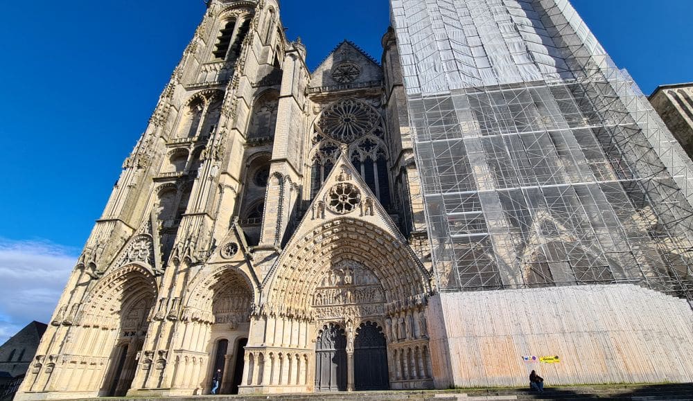 A gothic cathedral with the right-hand tower obscured by scaffolding.