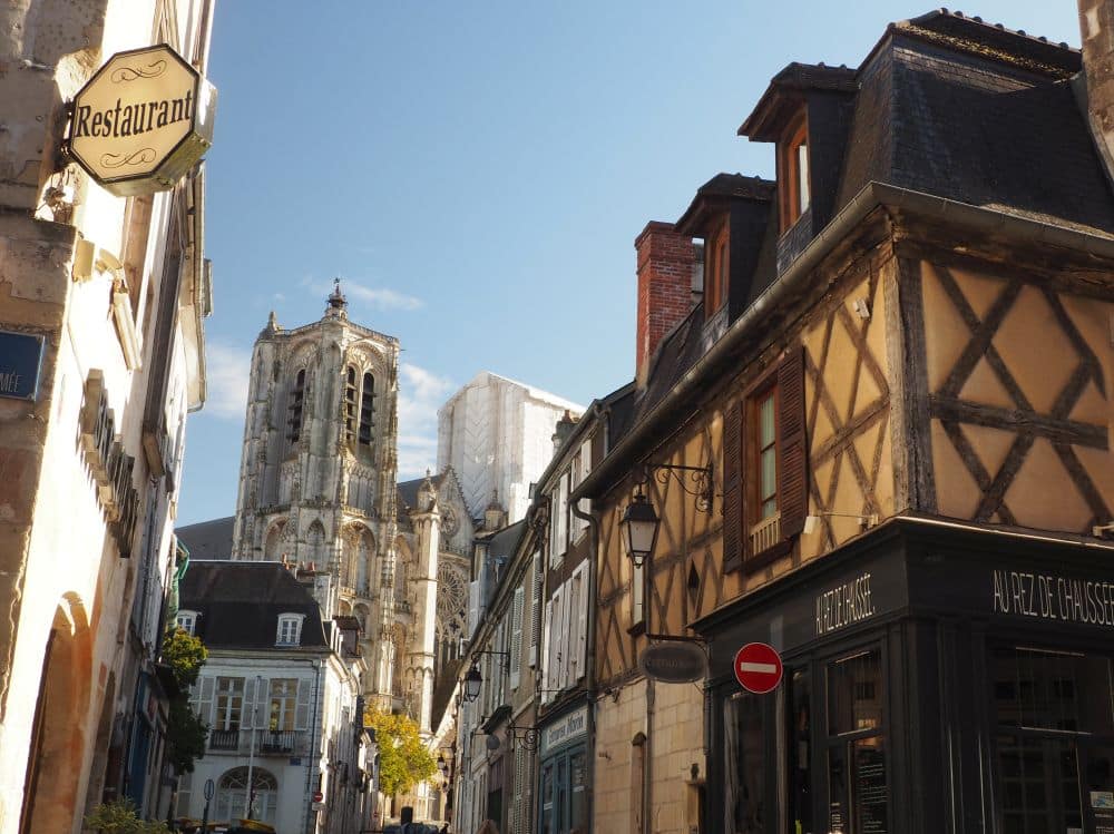 A half-timbered house above a storefront, and the cathedral in the background.