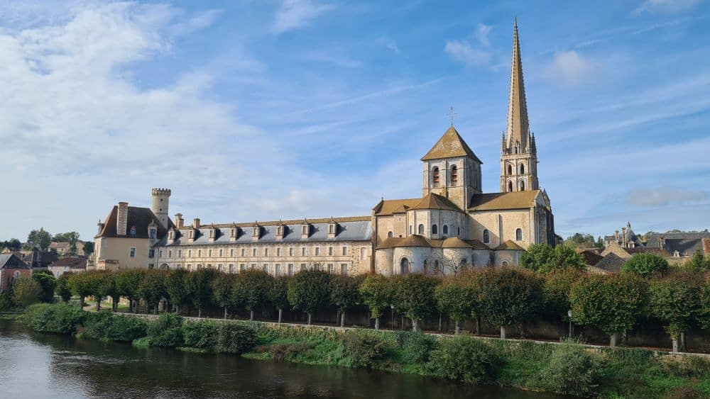 A view of the church - a long, low building with one pointy spire and one square tower.