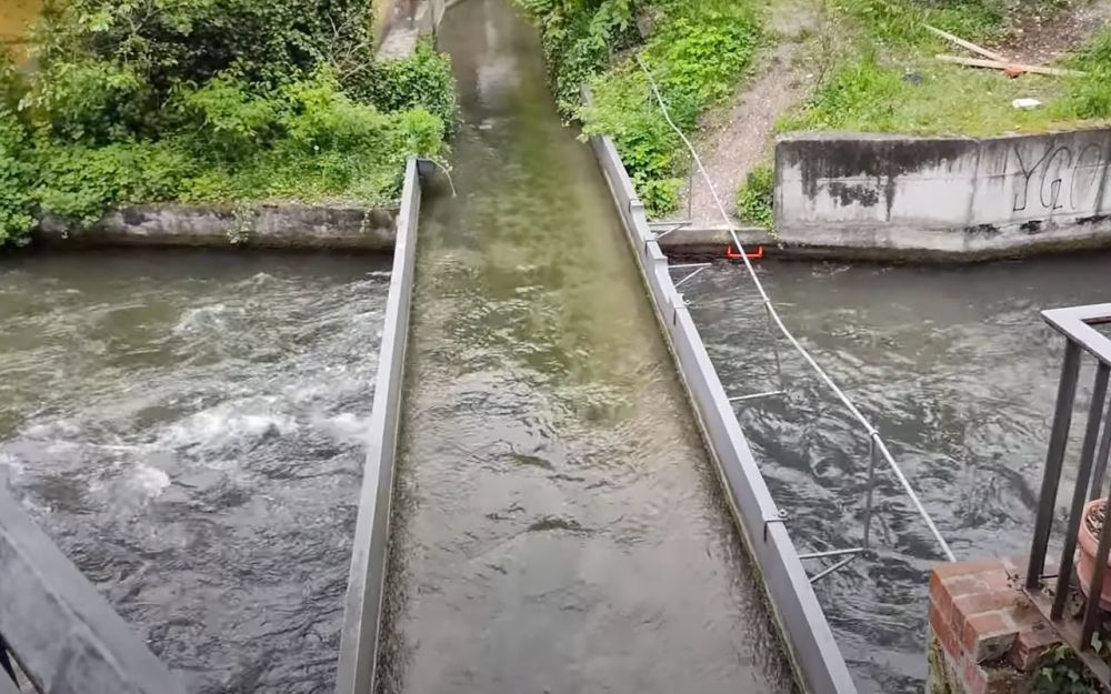 A small bridge carries water over a wider canal below it.