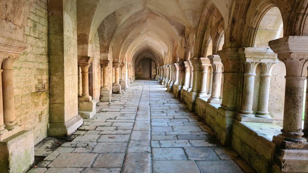 A long paved room, arched, open to the outdoors on the right, between pillared arches.