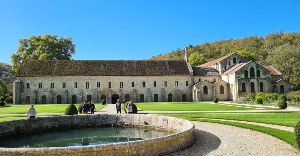 The abbey as seen across a garden: long building with 2-3 storey and the church at one end.