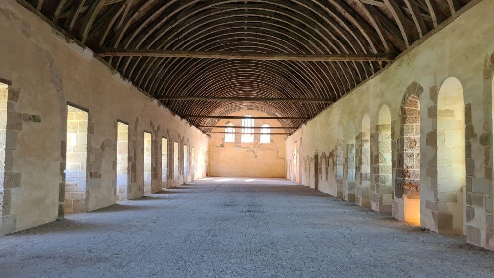 A large, long room with arched wooden roof and windows along both sides.