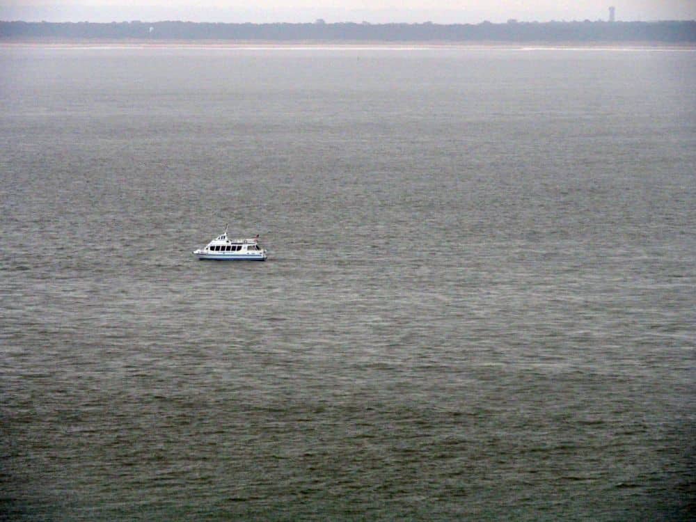 A boat on a gray sea, with land visible in the background.