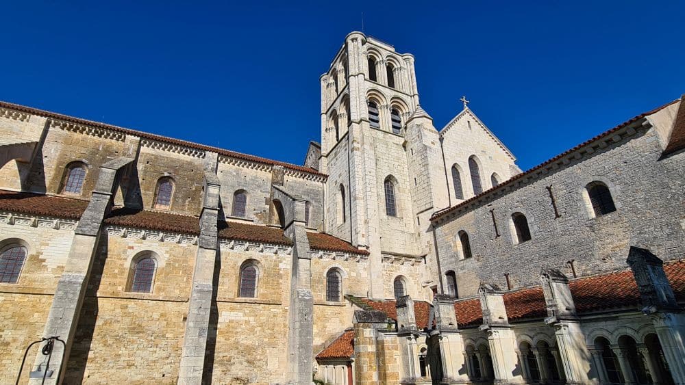 Side view of the church, with its square tower and a cloister walk on one side.