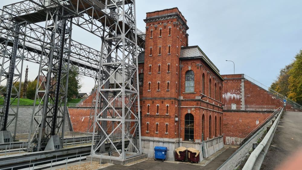 A boat lift - metal framework - with a red brick building next to it.