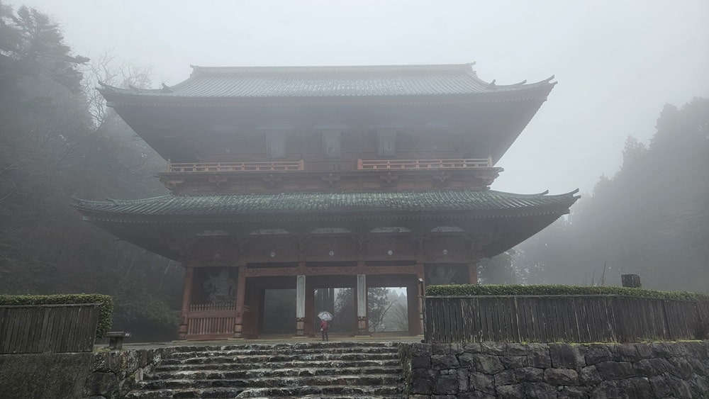 A Japanese shrine with the typical upcurved eaves surrounded by fog.