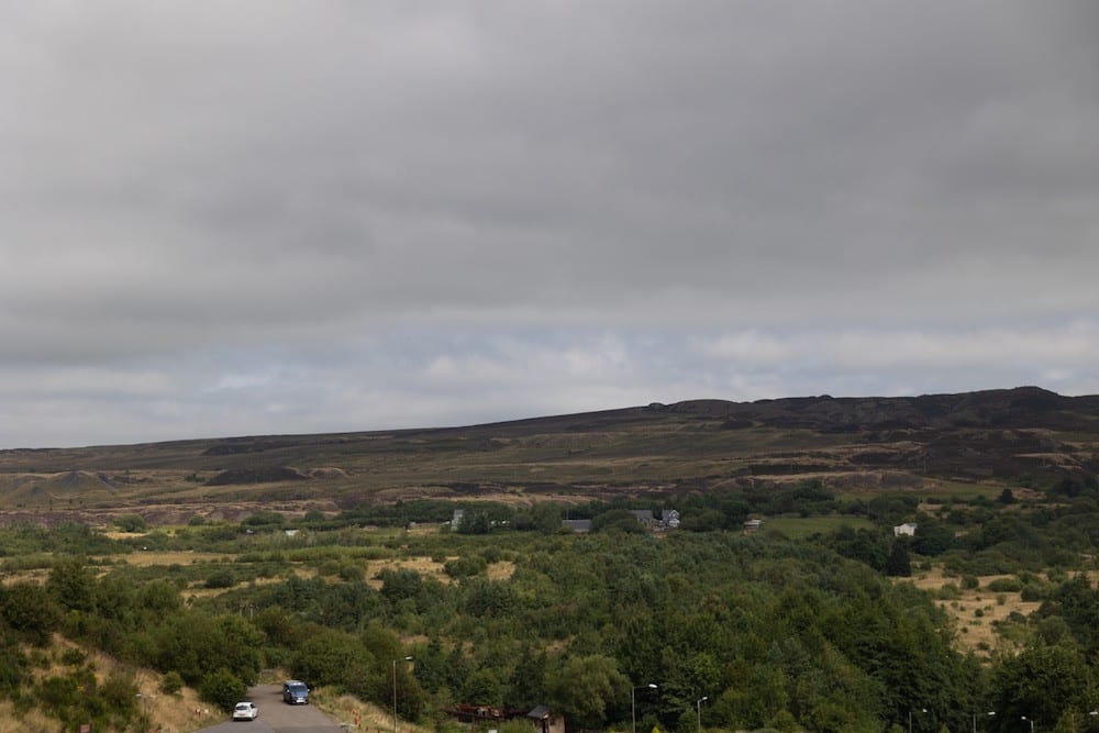 A view over a slightly hilly landscape with occasional small buildings.