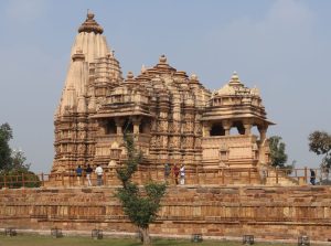 A temple covered in sculptures, with a tall stupa at the back and a dome in the middle.