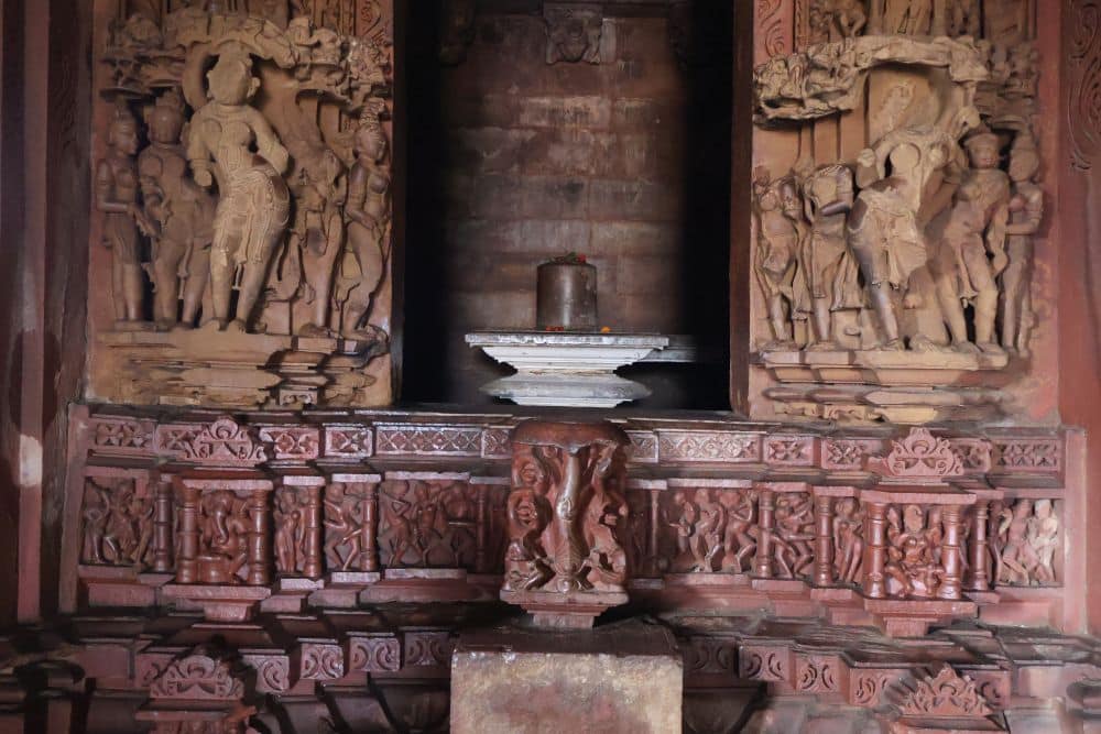 Inside a temple, the entrance to the sanctuary: detailed carvings around the door, a lingam visible inside.