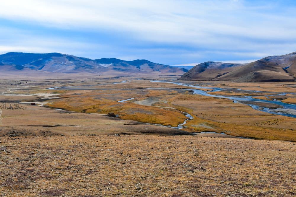 A view of Orkhon Valley - a brown grassy plain with mountains on either side.