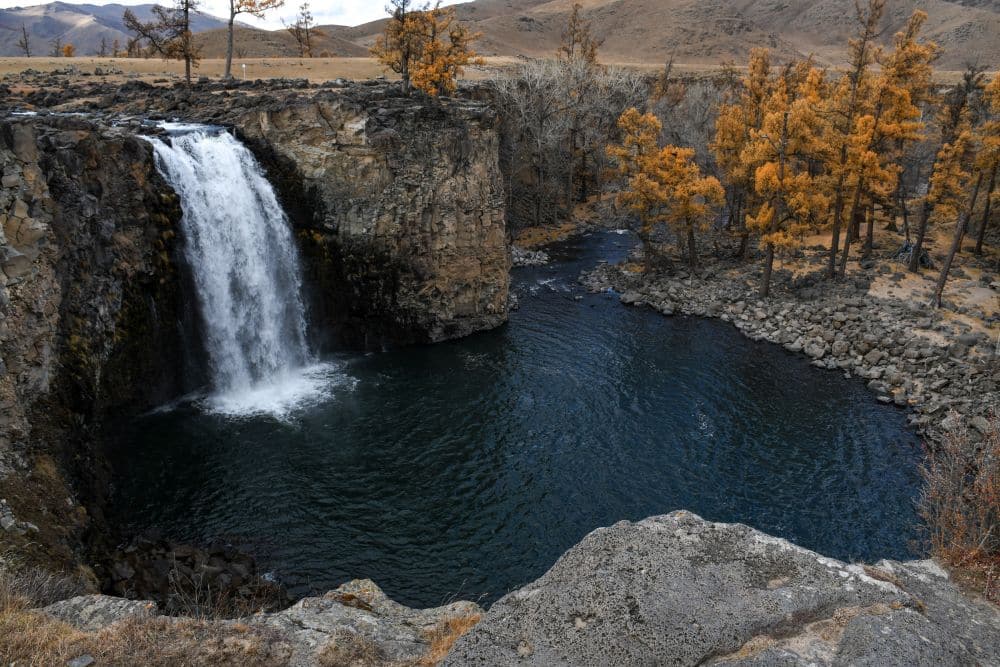 A waterfall tumbles into a dark pool below.