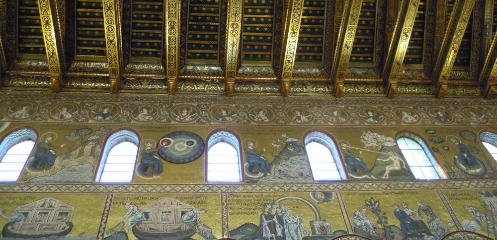 Looking up at a wall and part of a ceiling of a chapel covered with gold mosaic and images from bible stories.