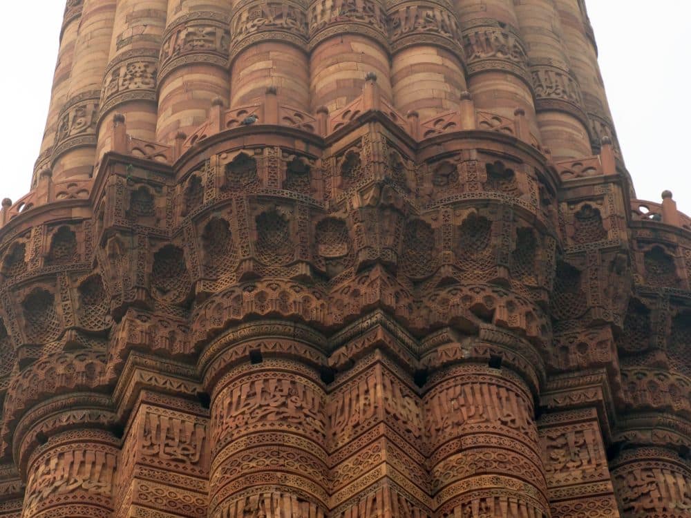 A decorative balcony divides two parts of the tower: below, alternating rounded and square fluting. Above, only rounded.