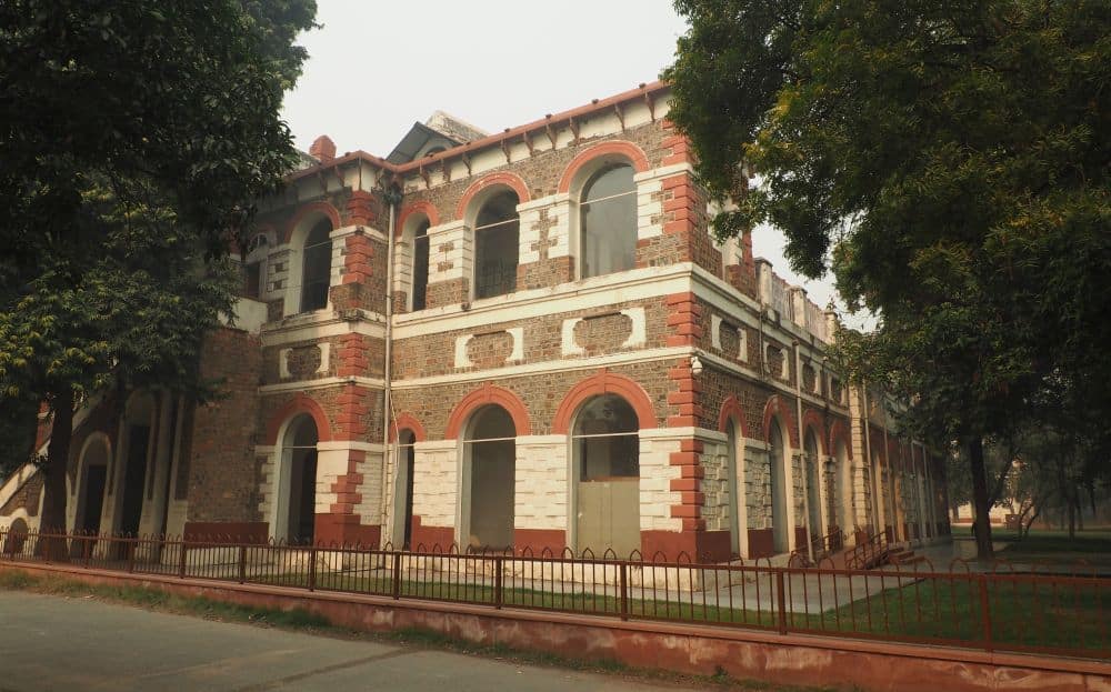 A two story building in alternating white and red stone, with arched windows.