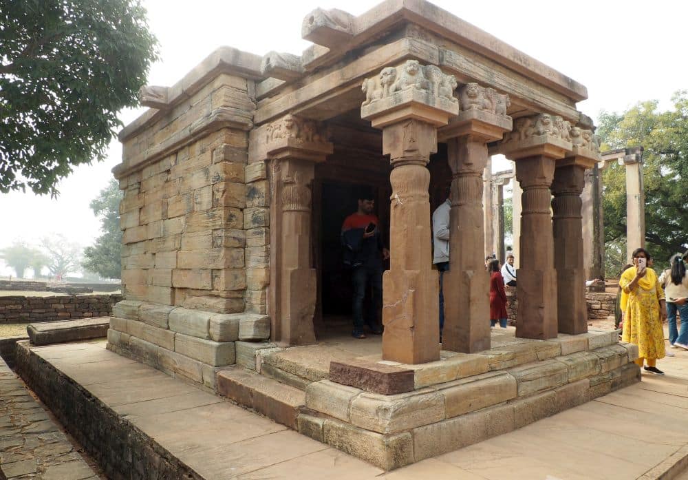 A small square stone building with 4 pillars across the front.