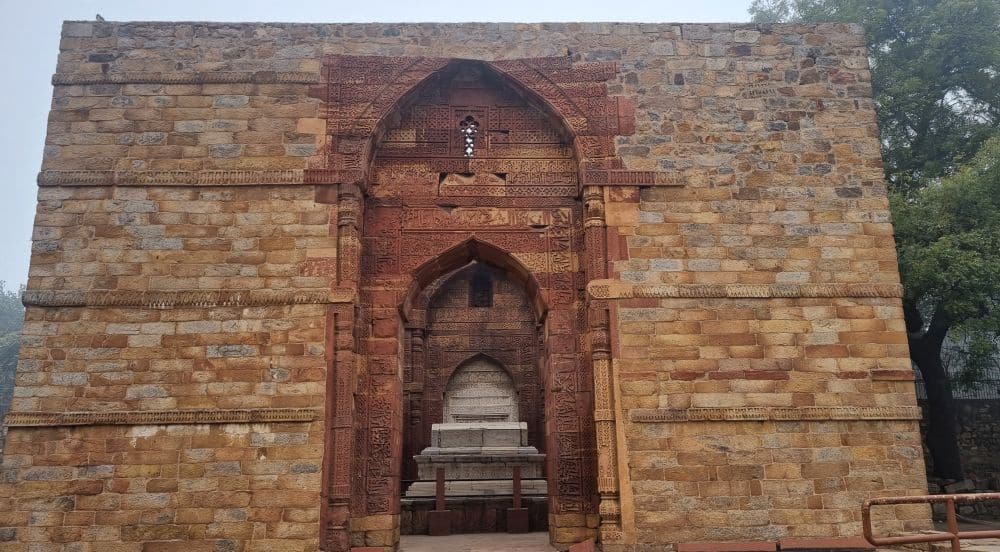 A decorative archway with, inside, a stone tomb.