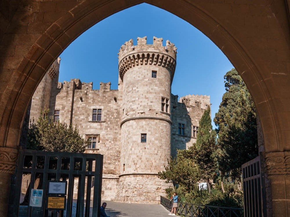 Looking through a gothic arch to a round stone tower with crenellations on top.