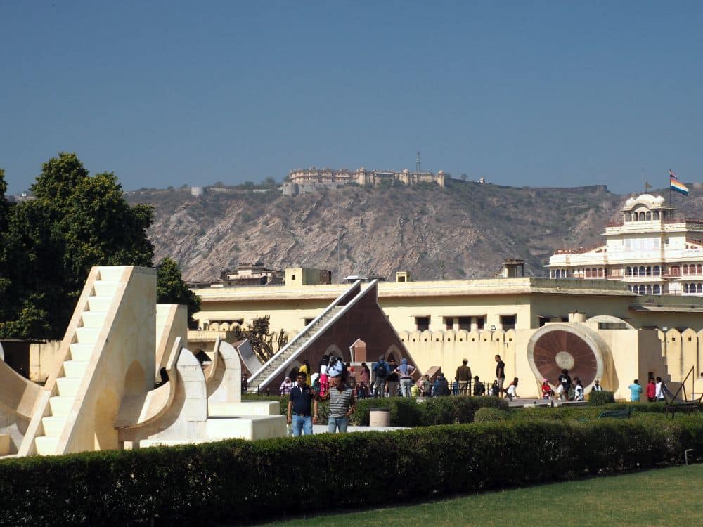 Several of the white-plastered instruments in an open courtyard with, in the distance on a mountain, a large fortress.