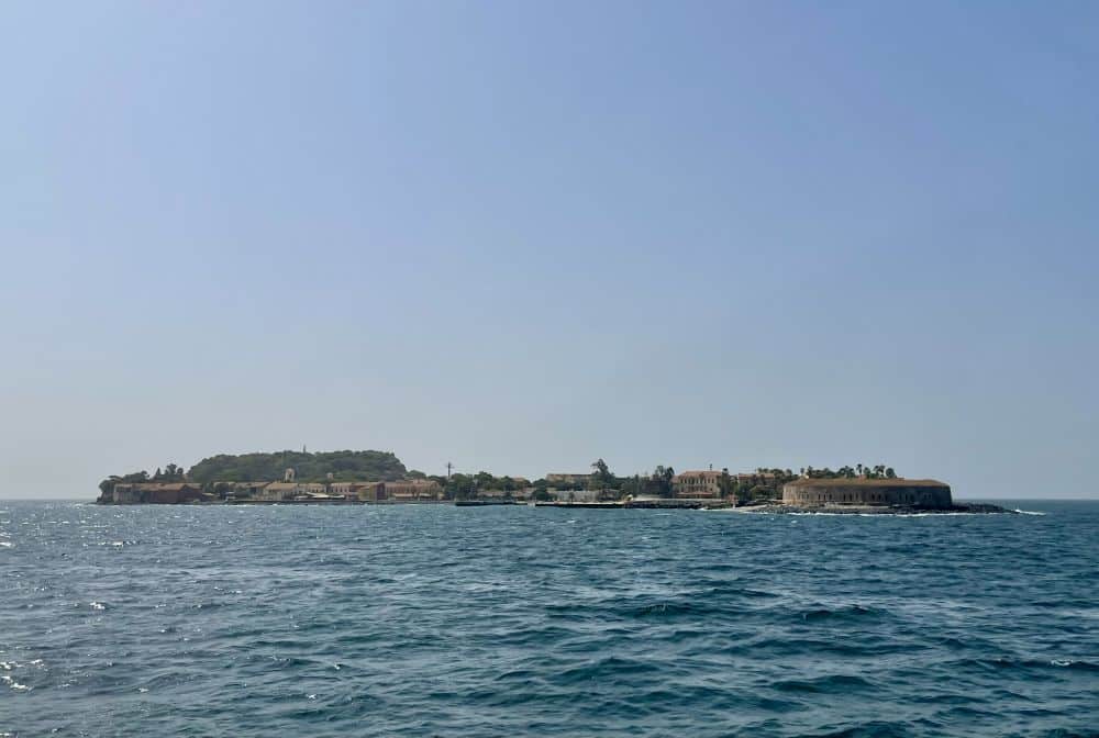 Seen across the water, a view of the whole island, with many low buildings visible.