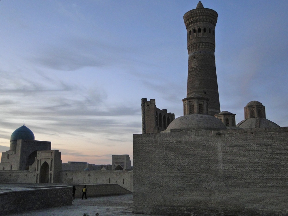 A mosque with a tall round minaret at sunset.