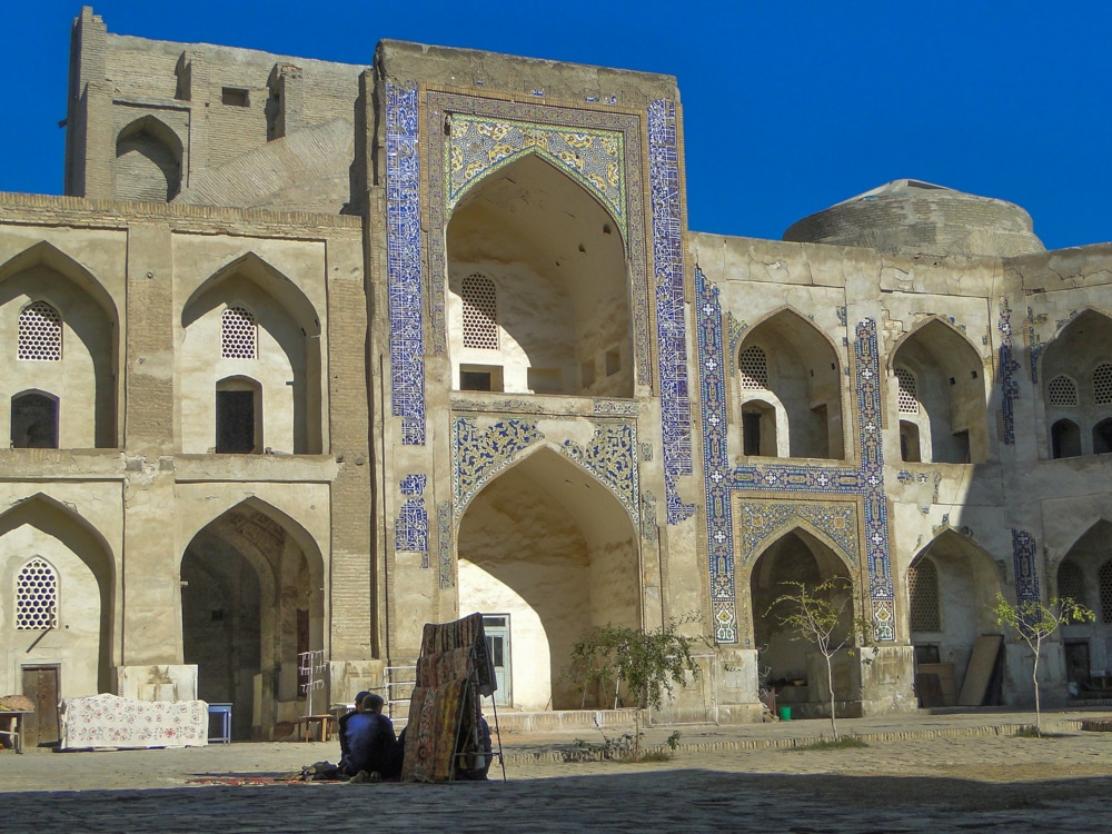 An elegant building with arched openings on two levels and blue mosaics on the facade.